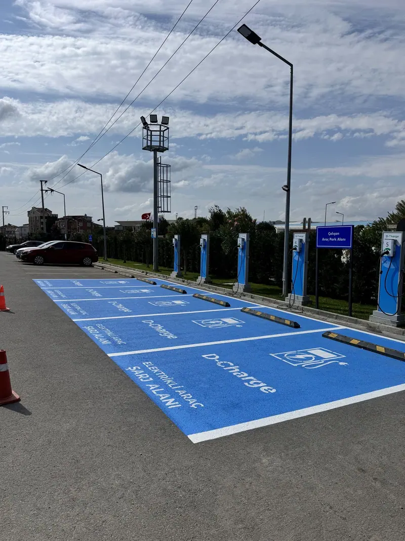 Açık otoparkta yan yana dizilmiş mavi elektrikli araç şarj alanları